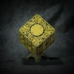 Intricate yellow geometric cube on display stand.