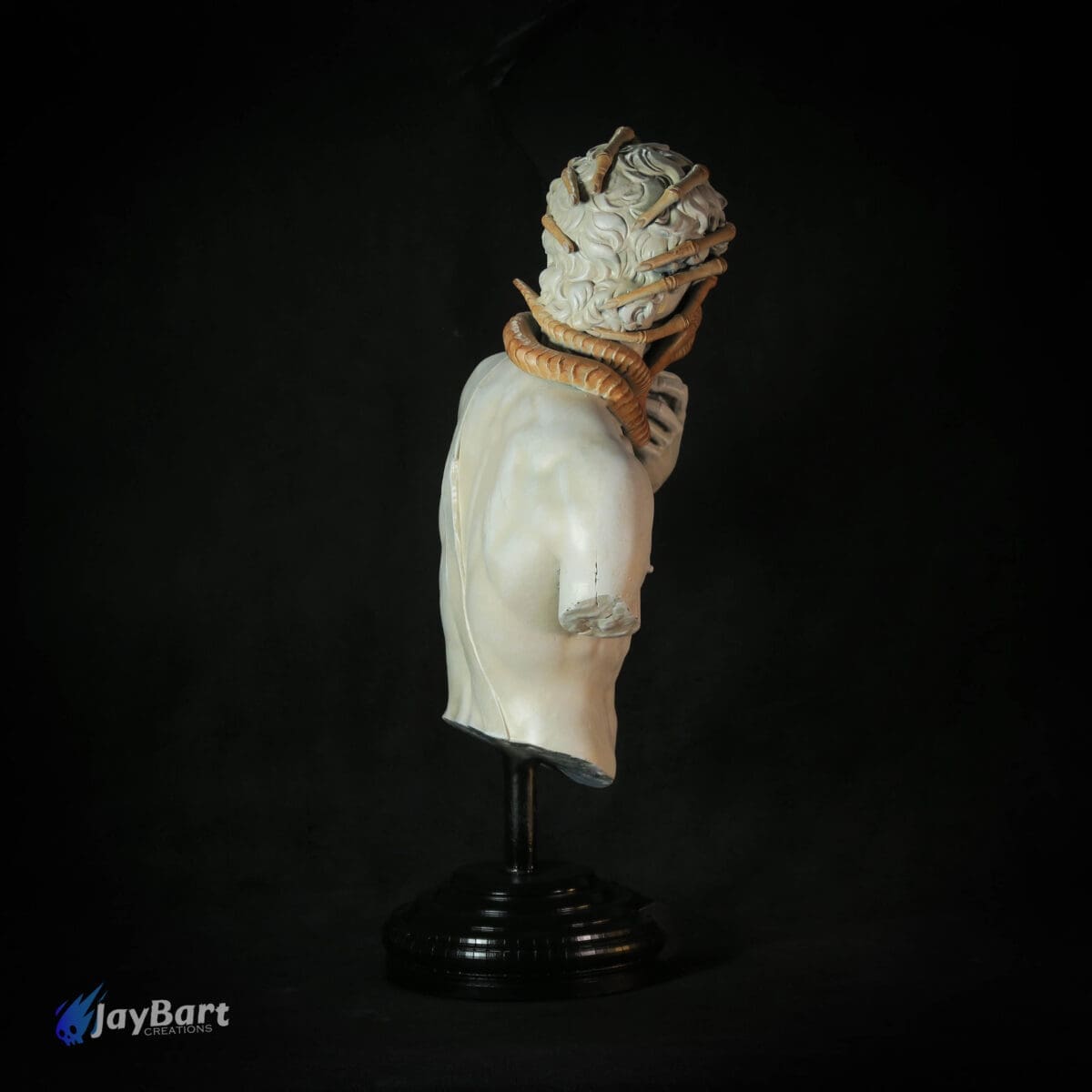 Sculpture with snake entwined in hair, black background.