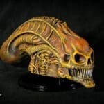 Detailed alien skull sculpture on black background.