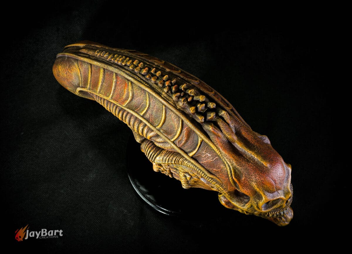 Detailed alien head sculpture on black background.