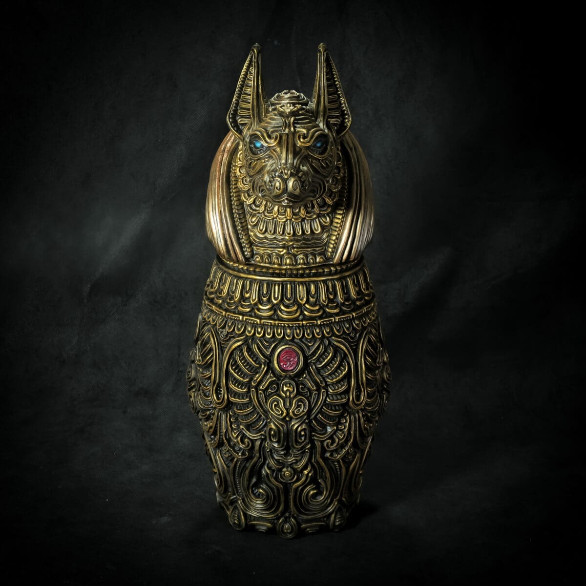 Intricate gold Egyptian feline sculpture with blue eyes.