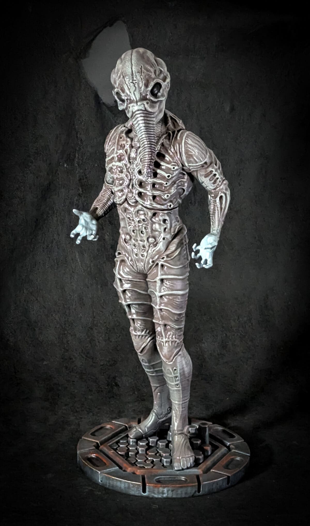 Alien sculpture with intricate design on dark background.
