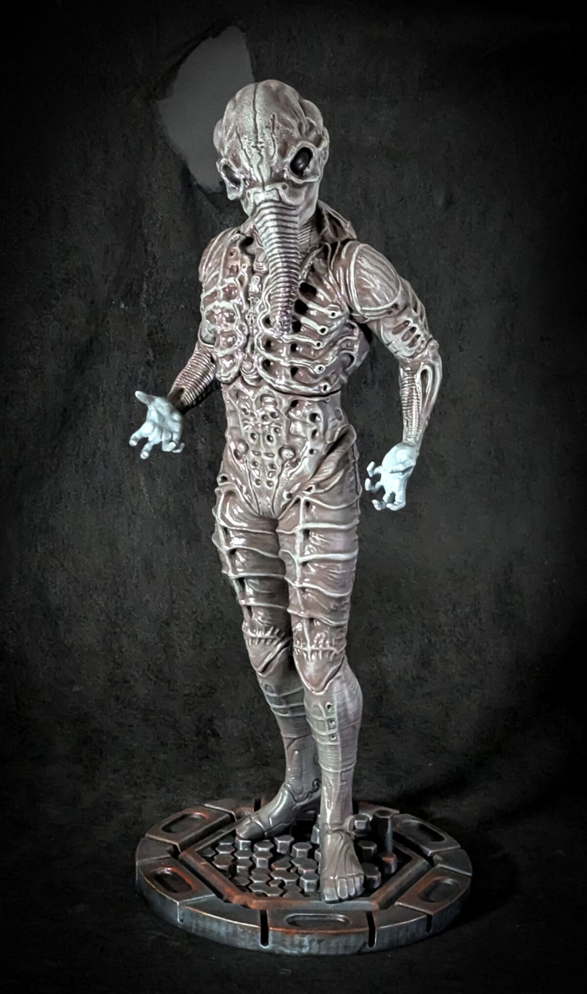Alien-inspired figure sculpture on textured base