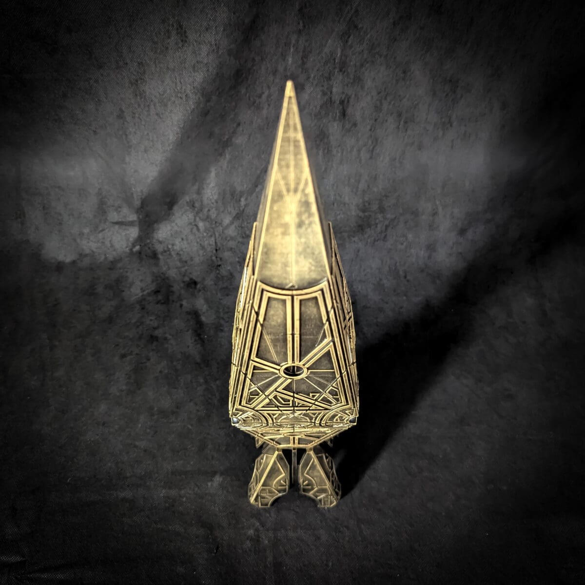 Intricate steampunk-inspired gold sculpture on dark background.