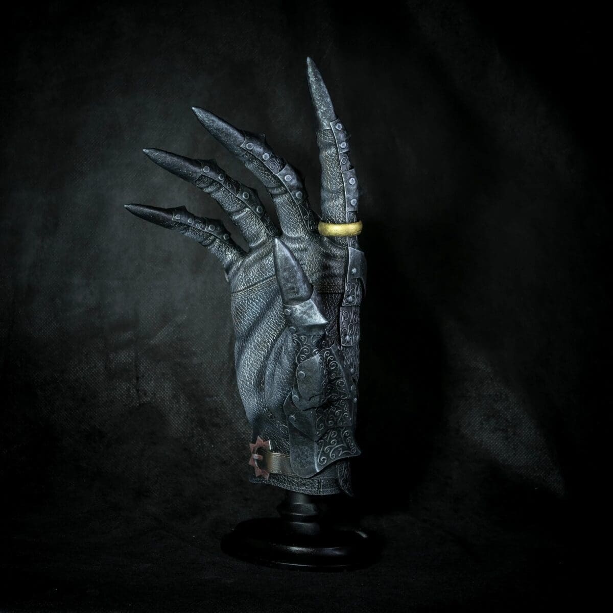 Ornate metal glove with a gold ring
