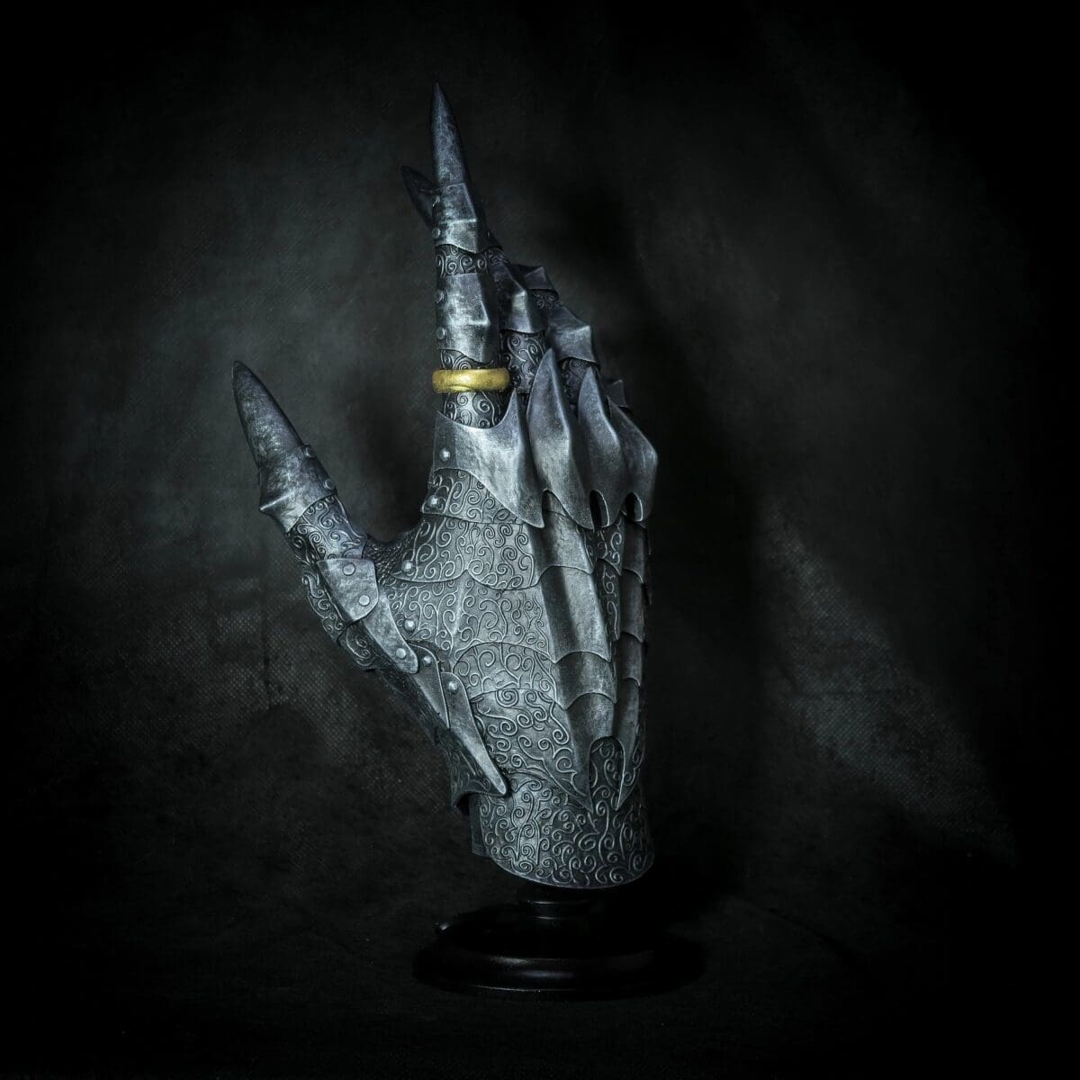 Ornate armored hand with golden ring.