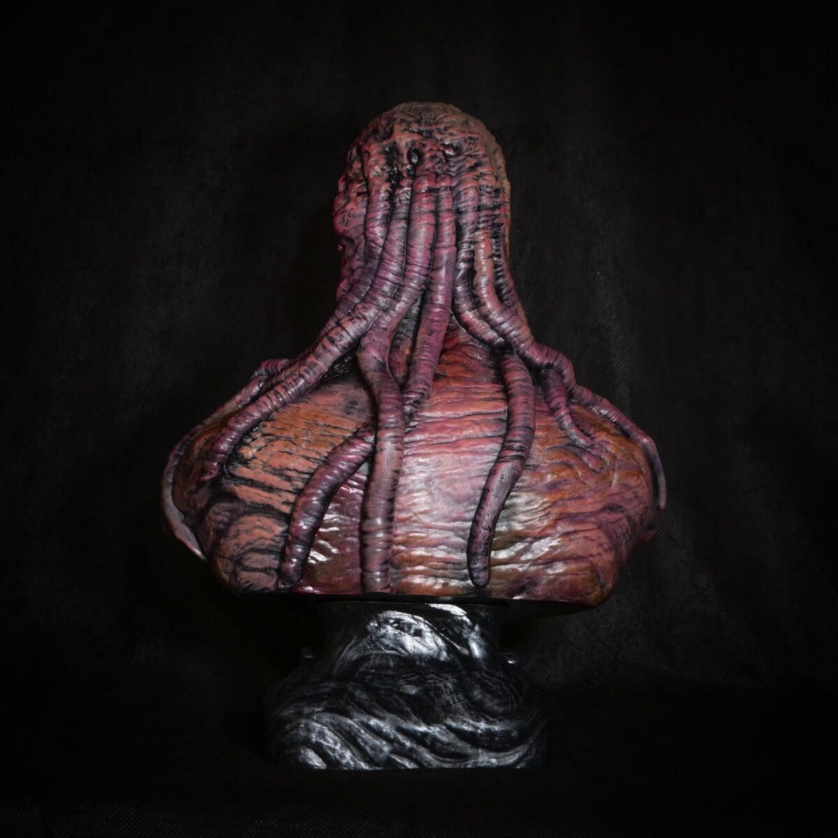 Tentacled sculpture on dark textured background.
