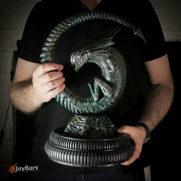Person holding a detailed alien sculpture