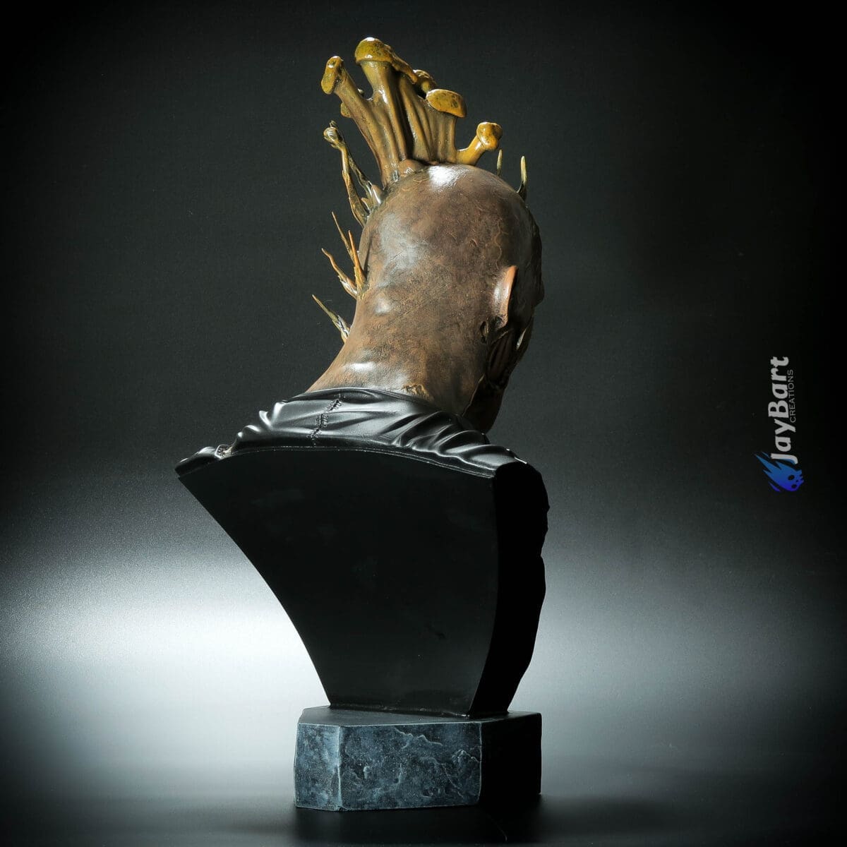 Sculpture of head with golden spikes and mohawk.