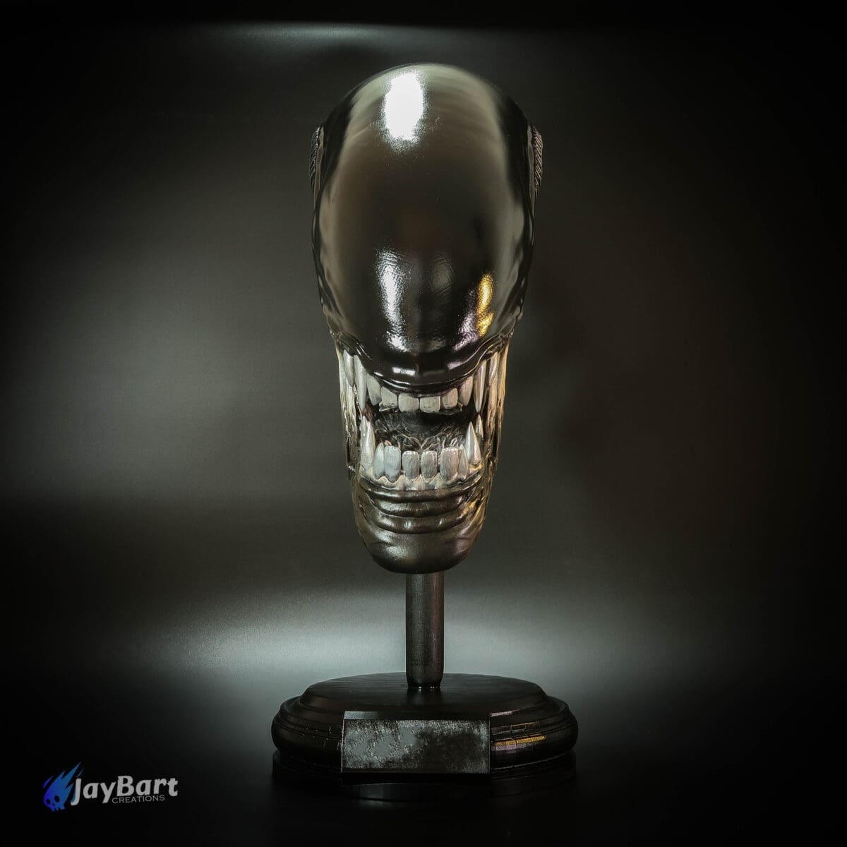 Alien creature head sculpture on display stand.
