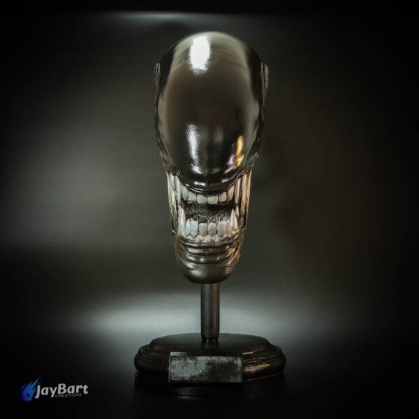 Alien creature head sculpture on display stand.