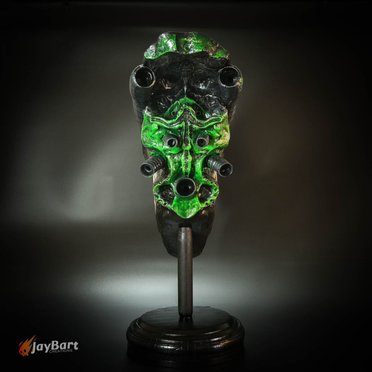 Alien-like mask with green accents on stand
