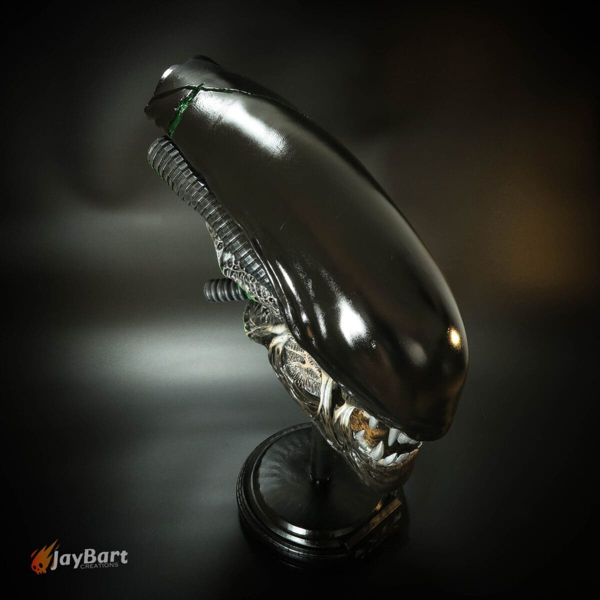 Alien creature sculpture with black shiny surface.