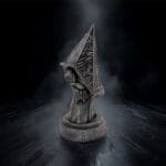 Dark, mysterious hooded figure statue on black background.