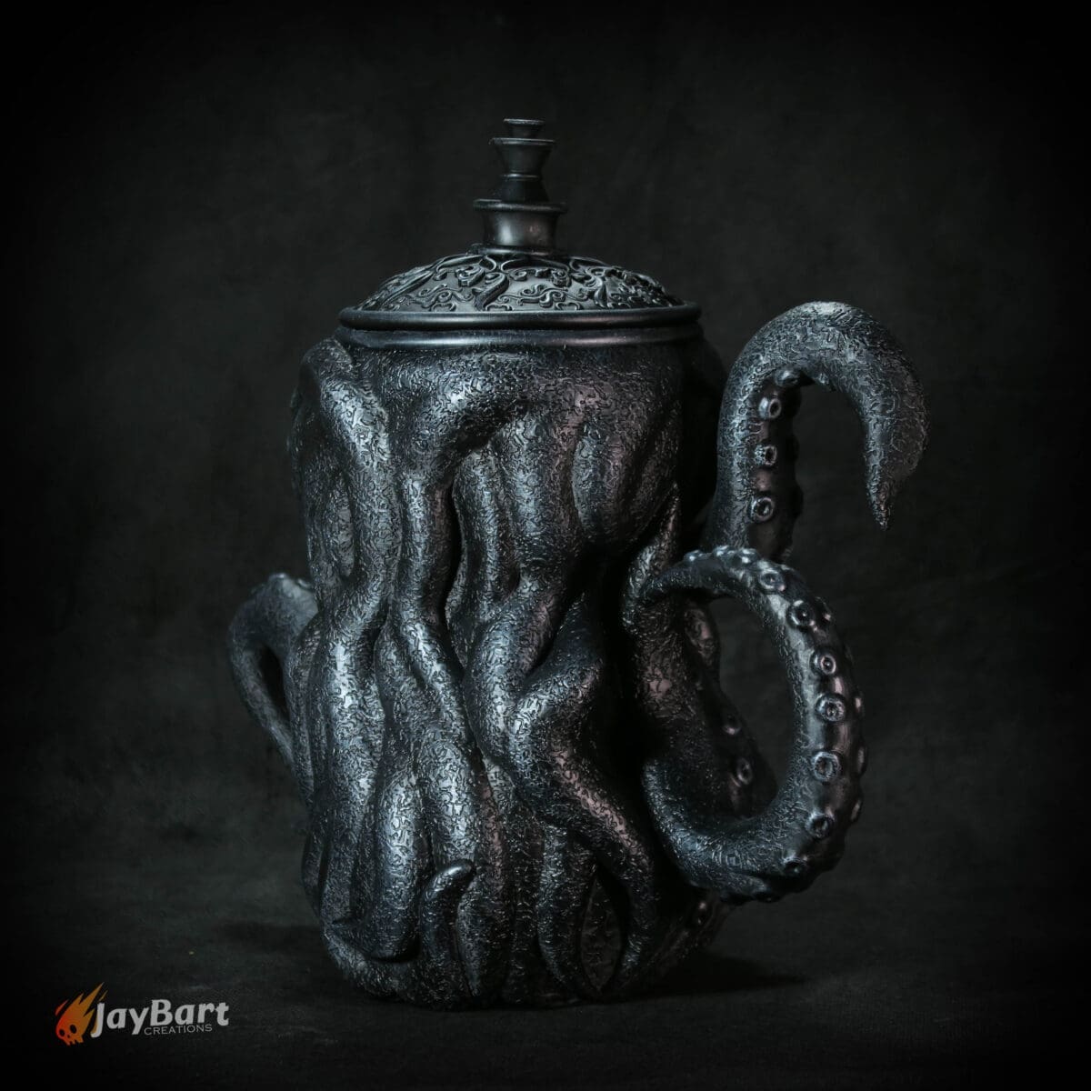 Dark octopus-shaped ceramic teapot on black background.